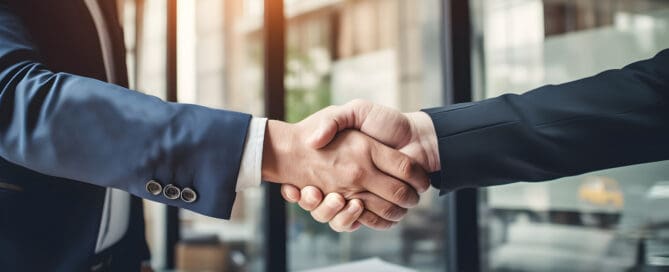 Two professionals shaking hands over financial documents, symbolizing a business deal or financial agreement with TP4 Advisors.