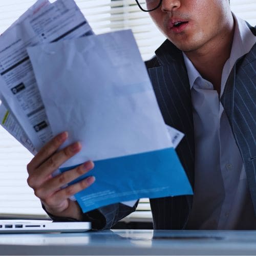A businessperson examining loan statements, representing the dangers of excessive debt.